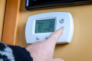 Hand lowering the temperature on a thermostat